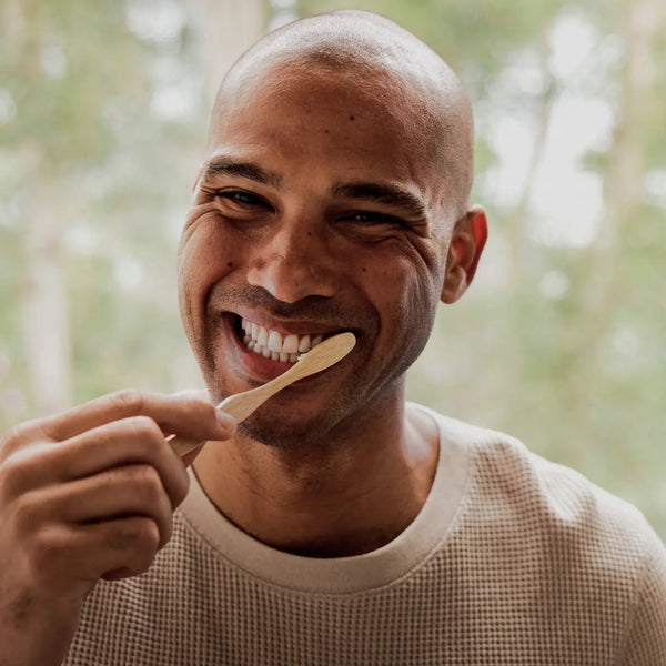 A man smiling and brushing his teeth
